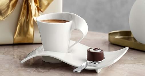 a cup of coffee on a saucer with a small piece of chocolate on it.