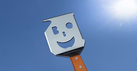 Metal spatula with smiley face cutout design against blue background, featuring wooden handle and geometric head shape.