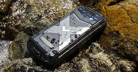 Smartphone robusto sobre rocas mojadas, que demuestra su resistencia al agua. El dispositivo tiene una funda protectora con un diseño en forma de X.