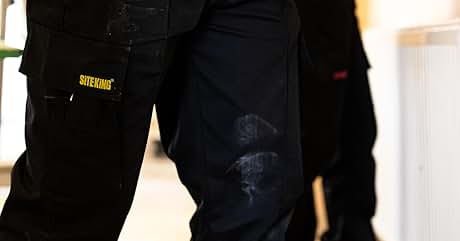 Close-up of black cargo pants with multiple pockets. A yellow 'SITE KING' logo is visible on one pocket.