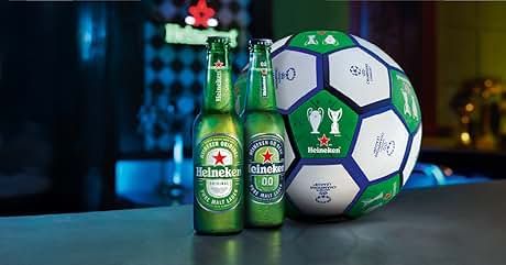 El texto dice «Heineken». Dos botellas verdes de cerveza Heineken junto a un balón de fútbol grande de la marca Heineken. El balón presenta paneles hexagonales blancos con el logotipo de Heineken y los símbolos del trofeo