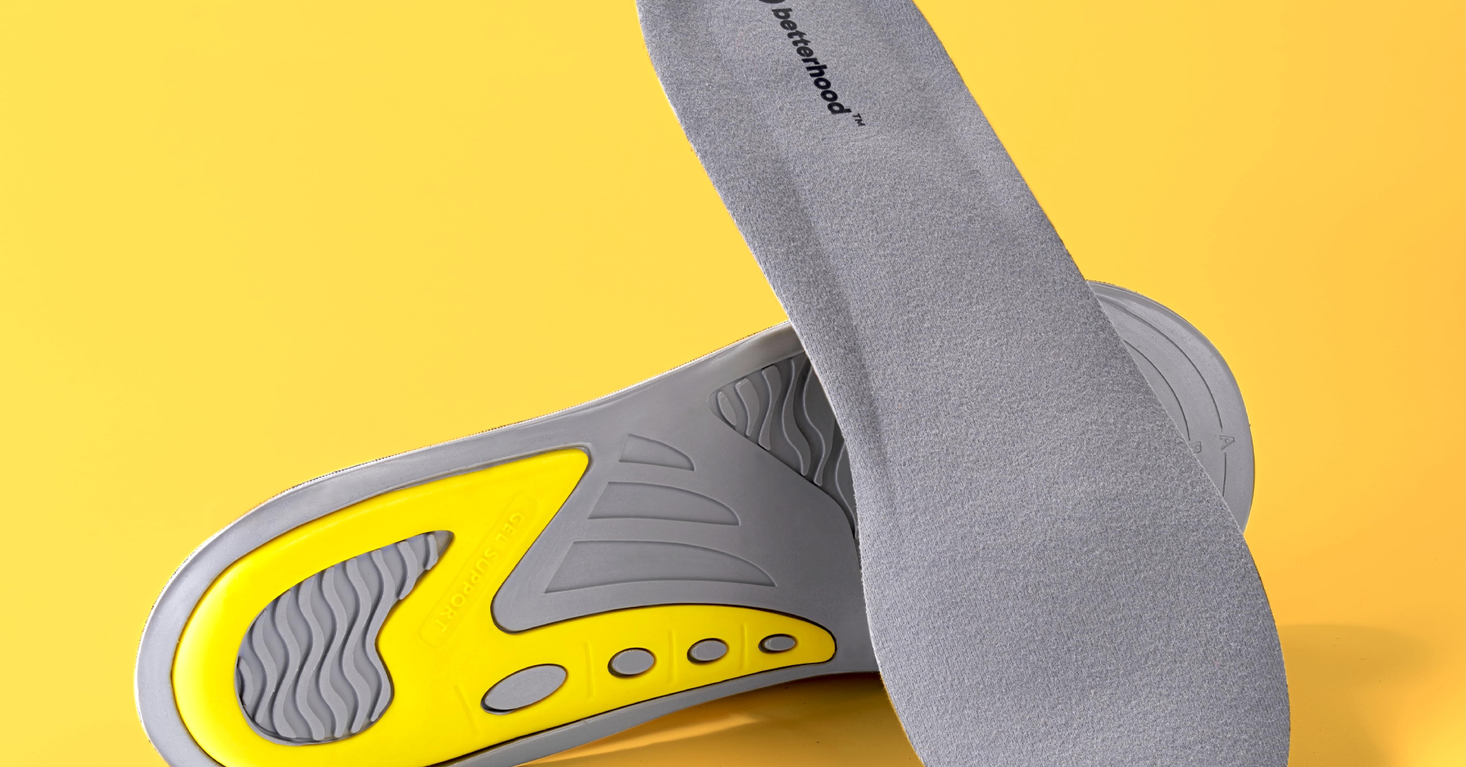 Gray cushioned insoles with yellow and white accents, featuring contoured design and perforations for comfort and breathability.