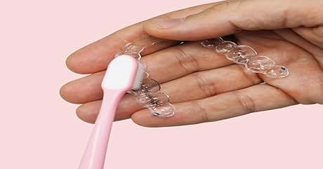 Accesorios para el cabello transparentes con forma de burbuja para sujetar en la mano. Pincel rosa tocando una de las herramientas transparentes y flexibles para el cabello.