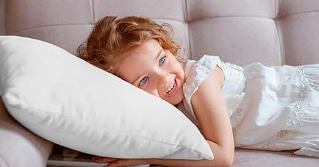 Sofá tapizado gris claro con respaldo capitoné. Almohada blanca en el sofá. El ambiente interior suave y de tonos neutros sugiere comodidad y relajación.