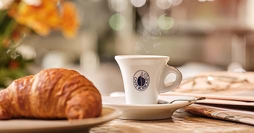 a cup of coffee and a croissant on a table