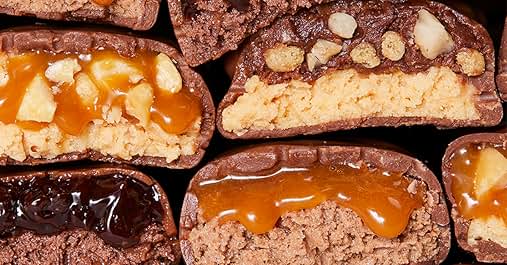 Assorted chocolate-covered confections with caramel and nut fillings. Cross-sections reveal varied textures and layers inside each piece.