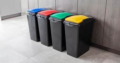Set of four large waste bins with colored lids: blue, red, green, and yellow. Black plastic containers for sorting recyclables and trash.