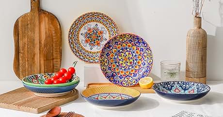 Colorful ceramic dinnerware set with intricate patterns, wooden cutting board, and wicker-wrapped bottle on textured surface.