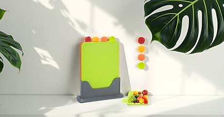 Set of color-coded cutting boards in bright green and gray, with matching circular tabs. Displayed with tropical leaves and fruit for context.