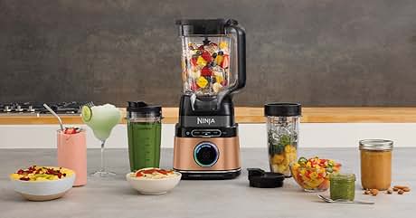 a blender with a bowl of fruit and a bowl of green vegetables.