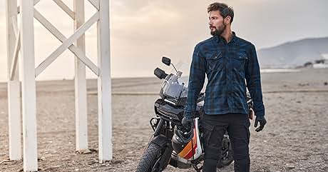 un hombre de pie junto a una moto en el desierto.