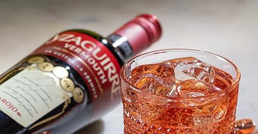 Botella de vermut Martini Fiero junto a un vaso lleno de hielo y líquido de color naranja, probablemente un cóctel hecho con