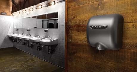 Baño público con varios lavabos y un secador de manos metálico Xlerator montado en una pared con paneles de madera. Paredes de azulejos