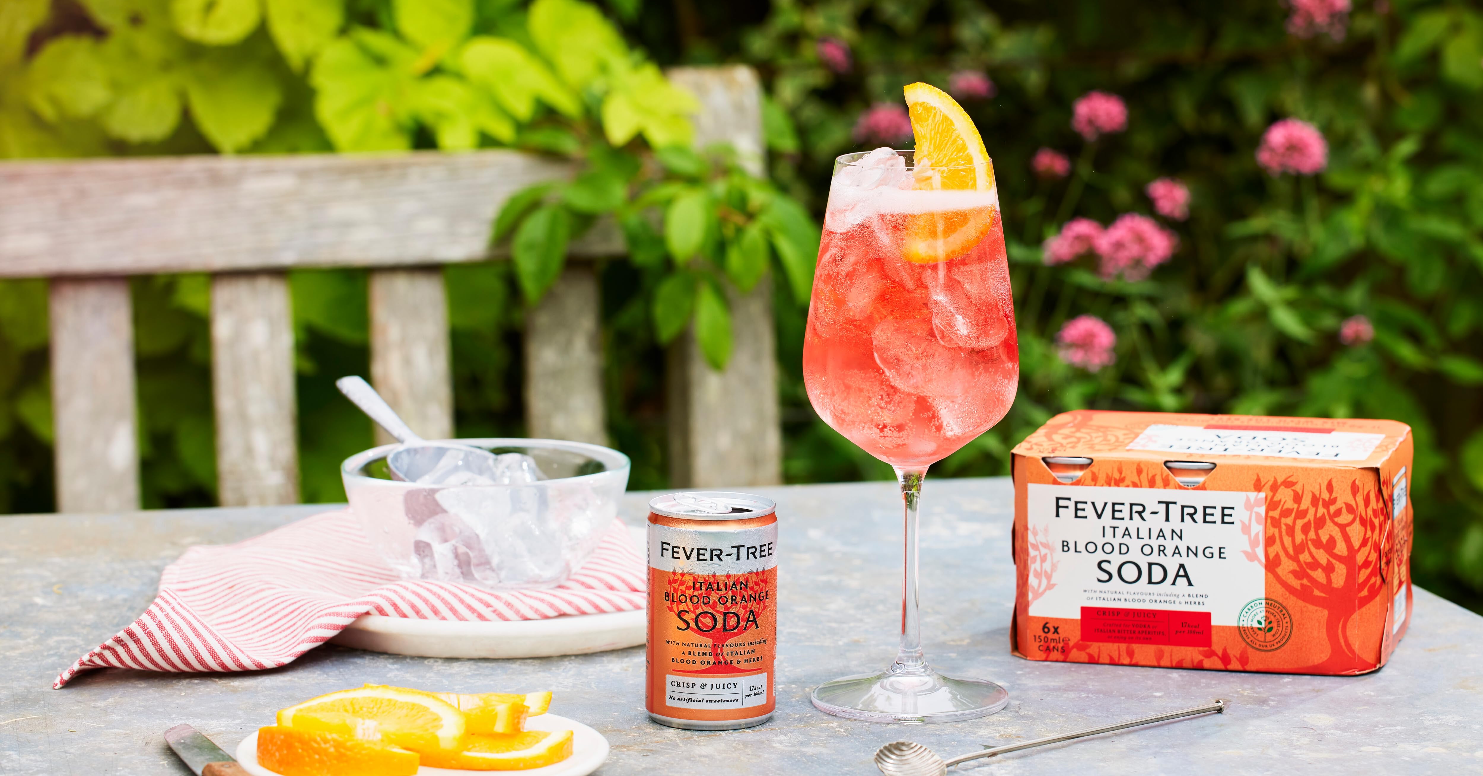 a glass of orange juice next to a bottle of fever tree soda.
