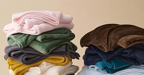 Pila de sudaderas o sudaderas con capucha dobladas en varios colores, incluidos rosa, verde, gris, amarillo, blanco, azul claro y marrón, dispuestas sobre una superficie clara