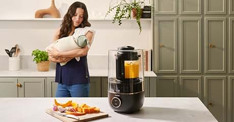 Text reads "Image 1". Kitchen scene with countertop blender containing orange liquid. Cutting board with sliced fruits. Green cabinets and shelves in background. Woman holding bowl in kitchen.