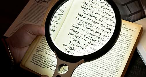 Illuminated magnifying glass held over an open book page, demonstrating reading magnification in low-light conditions.