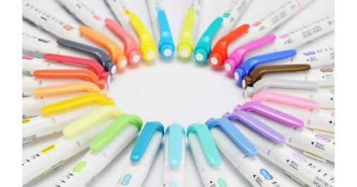 Circular arrangement of colorful gel pens or markers displayed in rainbow order, with translucent bodies and white caps.