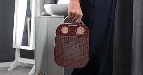 Sostenga de la mano una pequeña bolsa o bolsita de tela de color marrón rojizo con dos detalles metálicos circulares en