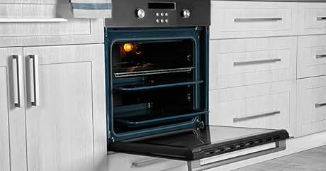 con acabado en acero inoxidable y controles digitales. Puerta del horno abierta, mostrando la luz interior encendida. Ubicado en gabinetes de cocina blancos con manijas de metal