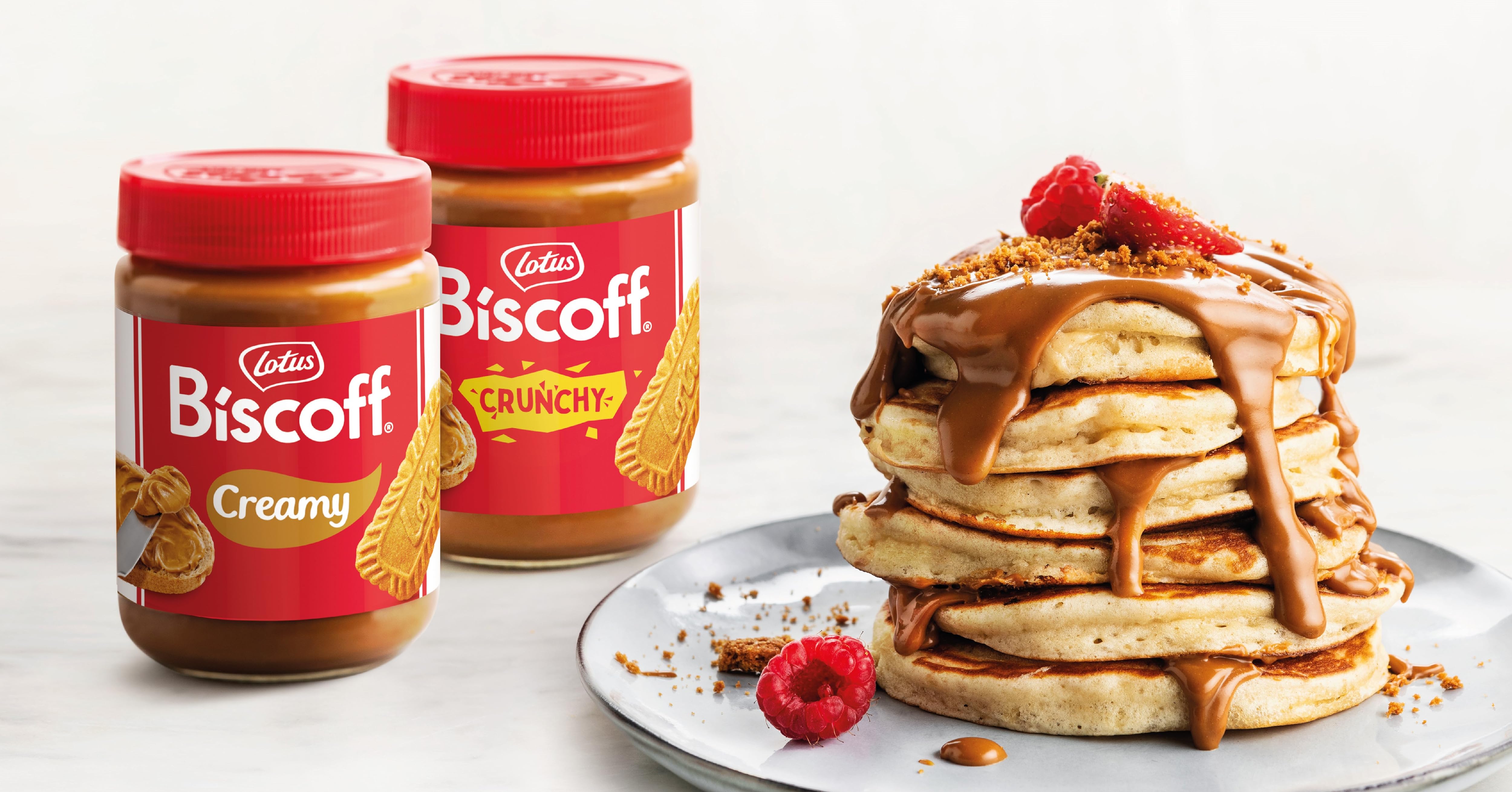 Dos tarros para untar Biscoff: variedades «cremosas» y «crujientes». Pila de tortitas con la pasta para untar visible a la derecha