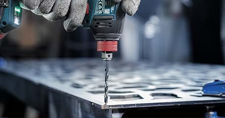 Primer plano de un taladro eléctrico en acción, perforando una lámina de metal. Las manos enguantadas sujetan la broca, con virutas de metal visibles alrededor de la