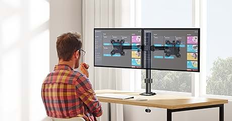 Soporte para dos monitores sobre un escritorio de madera, que muestra pantallas idénticas. Persona con camisa a cuadros sentada, trabajando en la configuración ergonómica en una habitación luminosa con ventana