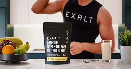 EXALT Premium Triple-Release Protein Blend package displayed on counter with fresh fruit and glass, featuring black packaging design.