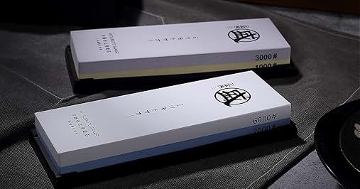 Multiple sharpening stones or whetstones displayed against dark textured surface. Text visible on boxes shows '3000#' and '8000#' indicating grit levels. White rectangular packaging with black logo.