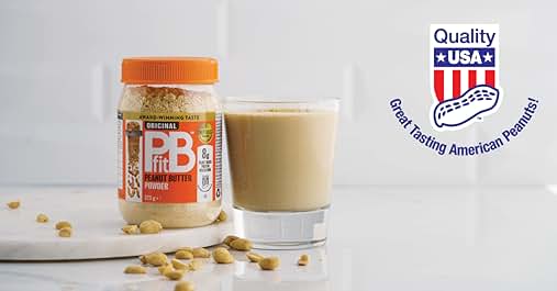 PB powder jar next to a glass of peanut butter shake. Scattered peanuts on white surface. 'Quality USA' logo with American flag design.
