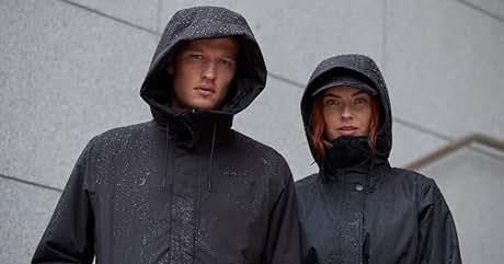 Dos personas vestidas con chaquetas impermeables oscuras con capucha y gotas de agua en la tela, de pie contra el fondo de una pared de concreto