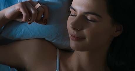A person resting on light blue bedding in a dimly lit bedroom setting.