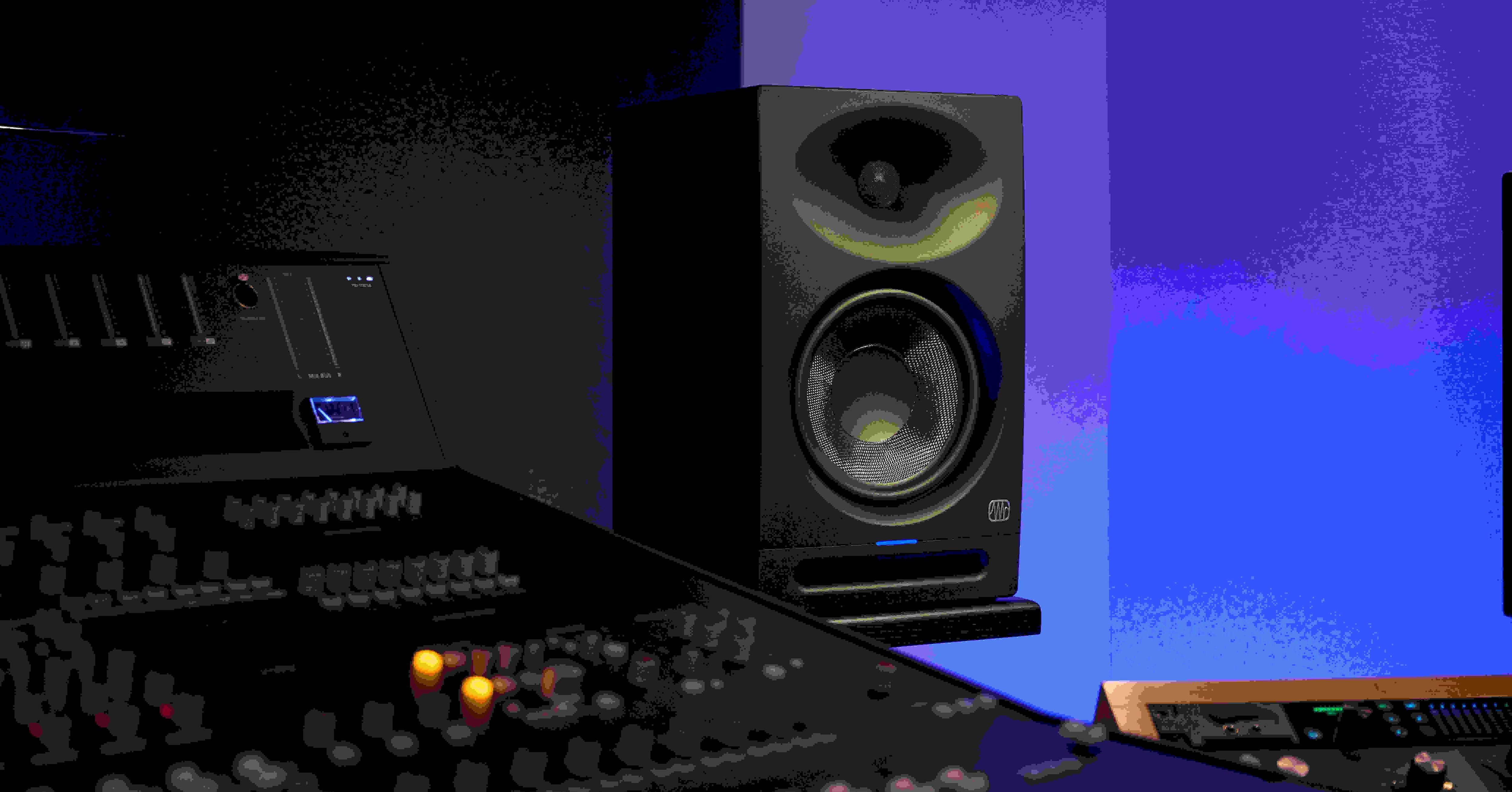 Professionelles Audio-Setup mit einem Mischpult im Vordergrund und einem Studiomonitorlautsprecher im Hintergrund vor einem blau getönten