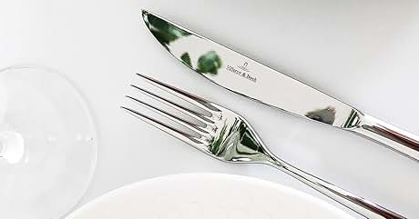 Tenedor y cuchillo plateados con mangos verdes sobre un fondo blanco, que muestran parcialmente el borde blanco de un plato.