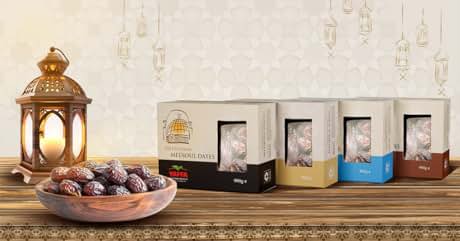 Display of packaged products in different colored boxes alongside a decorative copper lantern and plate of dates on a counter surface.