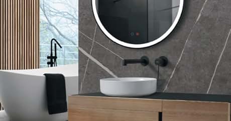 un baño con un espejo redondo y un lavabo