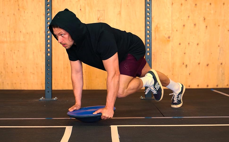 Wobble on the floor, an athlete has both hands on the wobble, 1 foot upwards and 1 on the ground