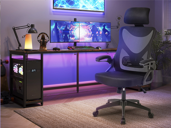 Gaming setup with blue-lit aquarium above, dual monitors, ergonomic chair, and PC tower. Desk has purple ambient lighting underneath.
