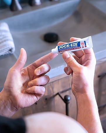 Hand using JOCK-EZE Flare Control Cream for Jock Itch applicator tube to apply cream to finger