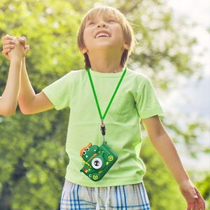 Enfant à l'extérieur vêtu d'un t-shirt vert et d'un short bleu, avec un dispositif vert en forme de monstre suspendu à un cordon autour du