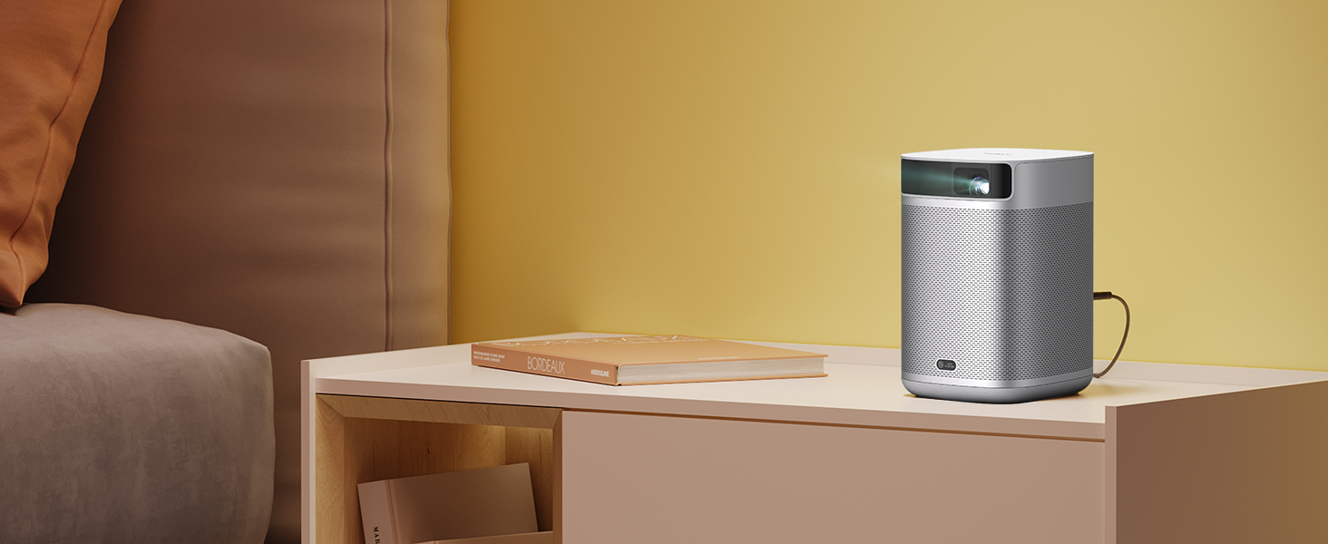 a smart speaker on a desk next to a book.