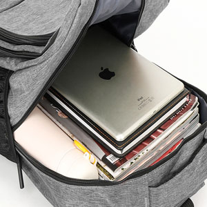 Sac à dos gris ouvert contenant un ordinateur portable, des livres et des papiers. Vue de dessus montrant des compartiments intérieurs organisés.