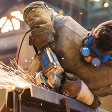 A metalworker wears protective clothing as sparks fly from his work with metal