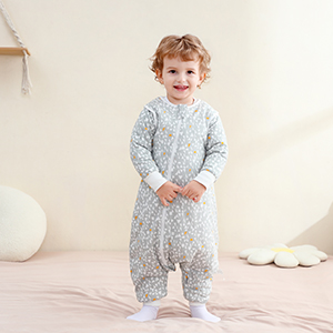 Child wearing light gray full-length sleepwear or romper standing against neutral background with decorative elements.