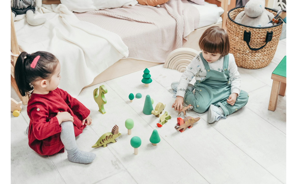 Indoor scene showing play activity on light colored carpet with green toy elements and decorative items scattered around.