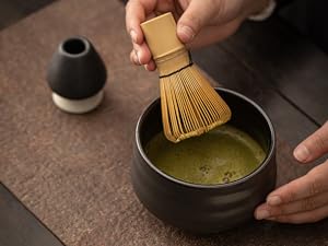 抹茶を泡立てる 70℃のお湯を70-80ml加えた後、茶筅を使って抹茶を素早く泡立てます。細かい泡が茶碗の表面を覆うまで、O字型に茶筅を動かし続けます。