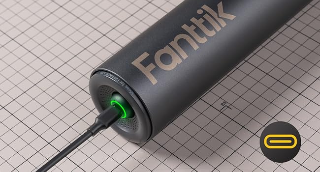 Zylindrisches schwarzes Fantik-Gerät mit USB-C-Anschluss. Grünes Licht im Anschluss sichtbar. Gerät auf Millimeterpapier-Hintergrund abgebildet.