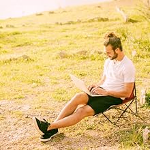 man outside in a chair with a laptop enjoying outdoor wifi access and connection