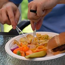 Cutting food with a clear plastic knife and fork on a plate with food