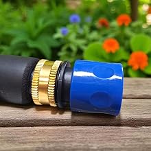 Close-up of a garden hose connector with black rubber grip and bright blue quick-connect fitting against blurred garden background.